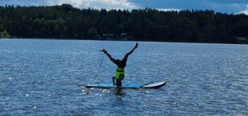 Person står på huvudet på en sup-bräda