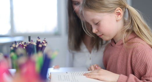 Lärare tillsammans med elev i klassrum.