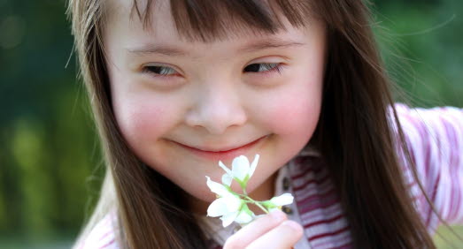 Leende flicka håller i en blomma