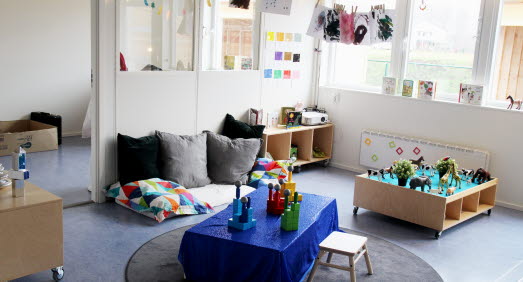 En kuddhörna, en lekö med djur, ett blått bord med färgglada klossar