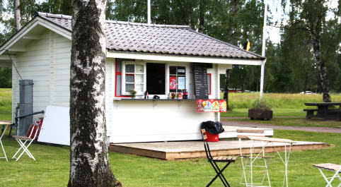 vitmålad cafékiosk omgiven av trädgårdsmöbler