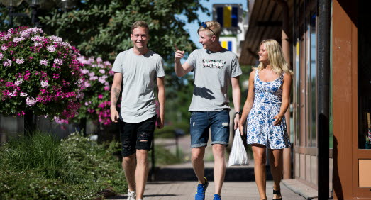 Tre glada personer som går bredvid varandra och pratar. 