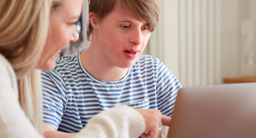 Kille med downs syndrom sitter vid laptop