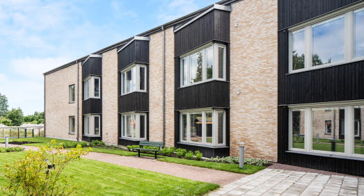 Exteriörbild som visar tegelfasaden på Djupängen och se stora fönstren i varje lägenhet,