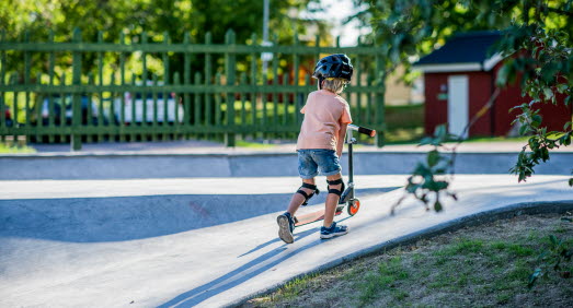 Barn går med sin kickboard i skateparken