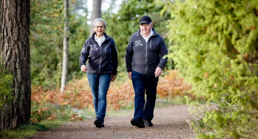 Äldre man och kvinna är ute och promenerar i ett motionsspår