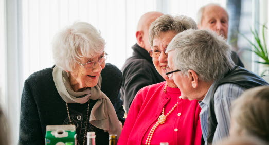 Tre äldre personer i livligt samspråk vid ett bord
