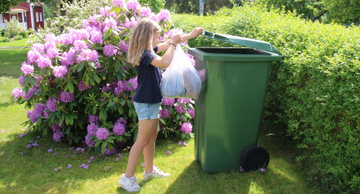Flicka som slänger skräp i sopkärl